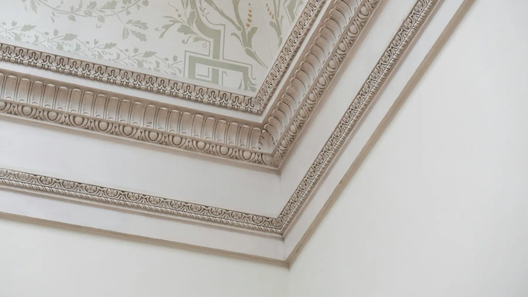 Corniche moulée à motifs de feuillages à l’angle d’un plafond ancien