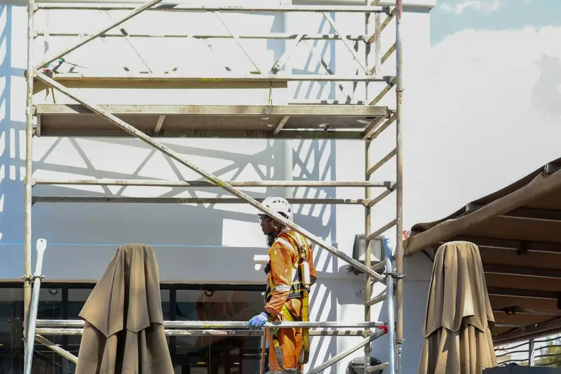 Ouvrier sur un échafaudage dressé contre une façade blanche