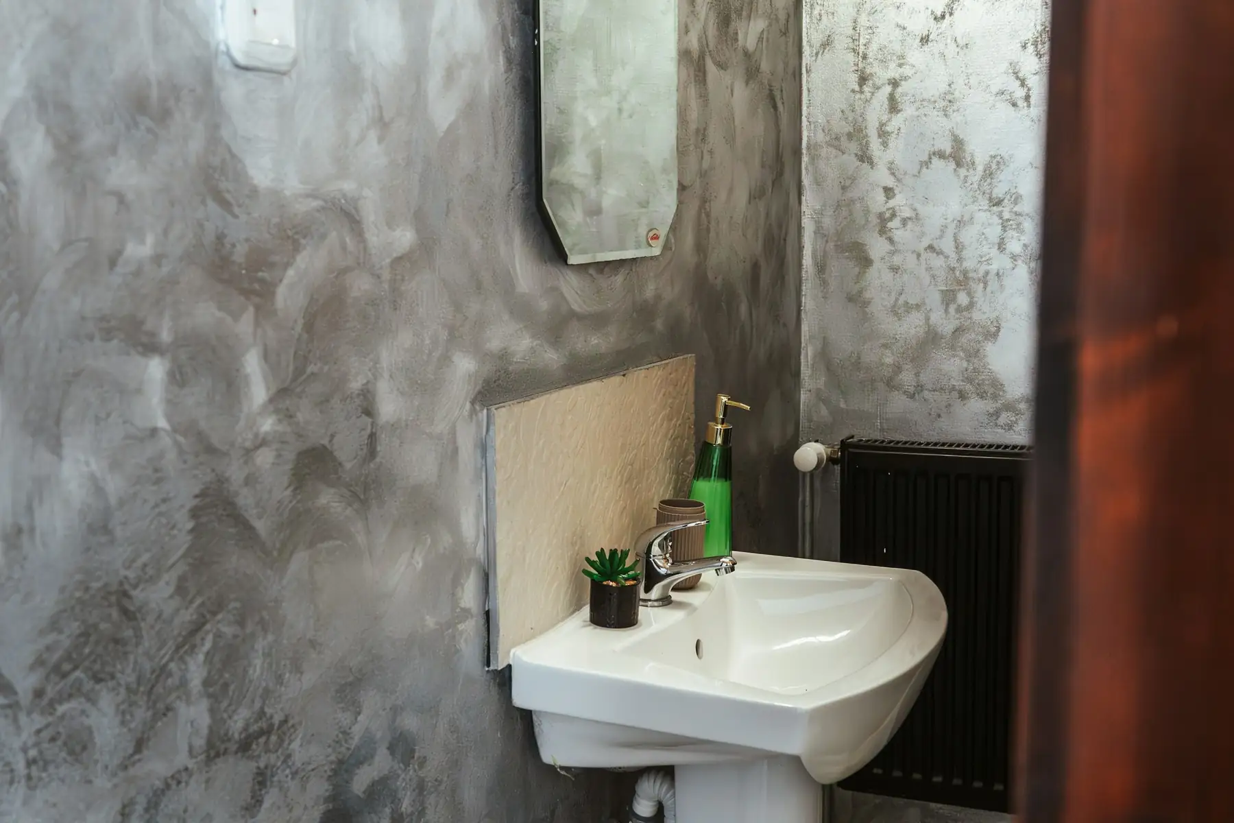 Salle de bains aux murs enduits et nuancés, lavabo blanc et miroir