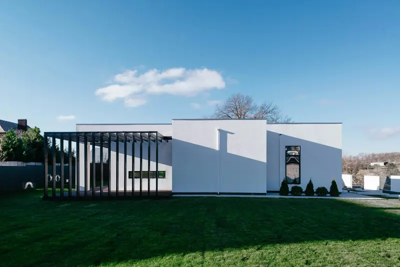 Extension blanche de plain-pied au toit plat, posée sur une pelouse sous un ciel bleu