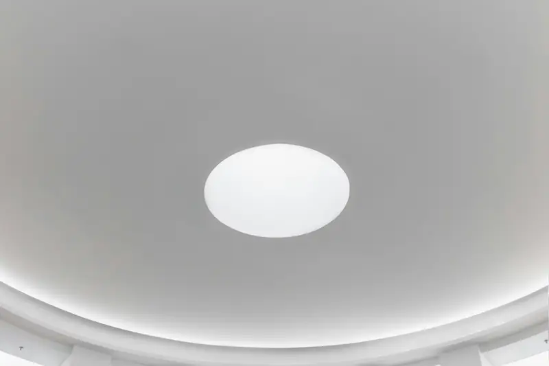 Plafond blanc parfaitement lisse, éclairage rond encastré au centre