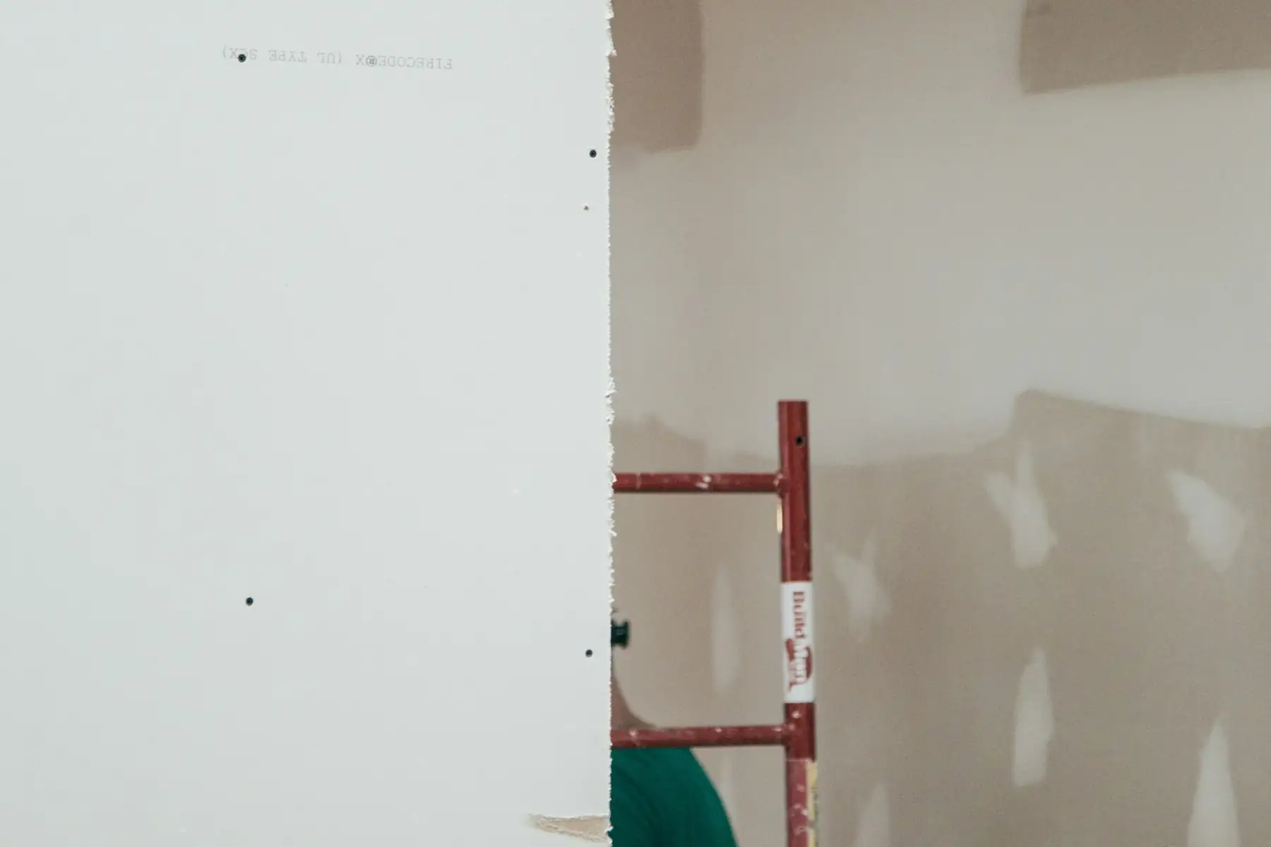 Plaques de plâtre posées, bandes et enduit de joint encore visibles, escabeau rouge