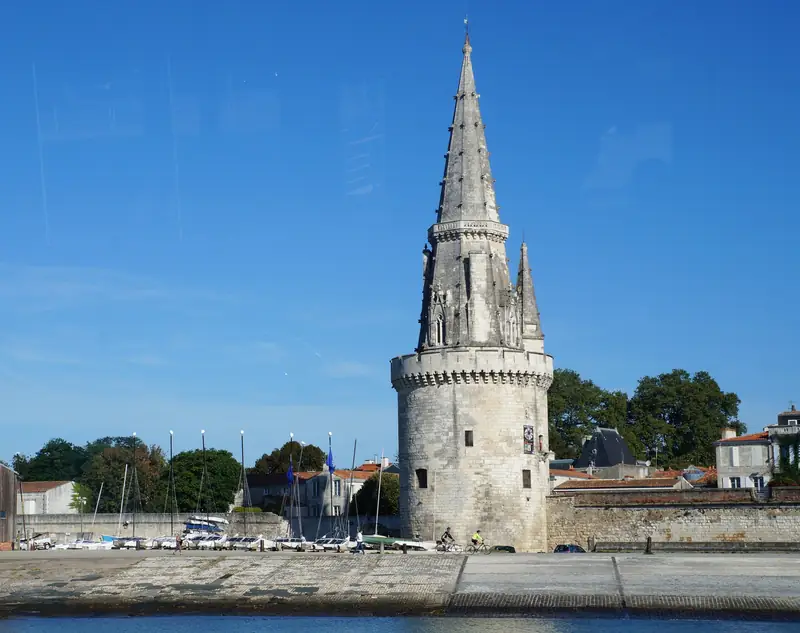 La tour de la Lanterne et sa flèche de pierre au bord de l’eau, ciel d’un bleu franc
